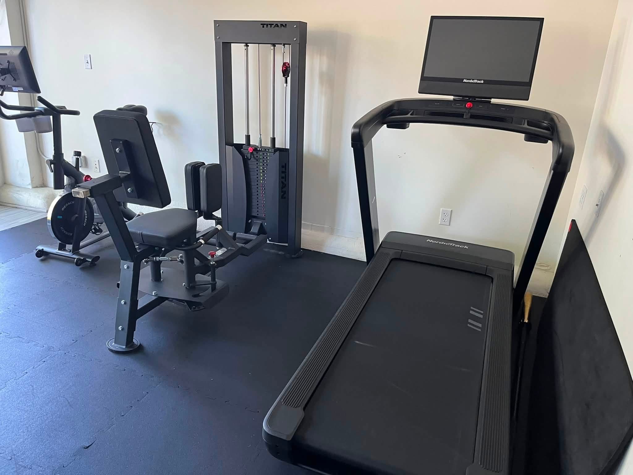 Treadmill, stationary bike and lower-body strength equipment inside the studio.