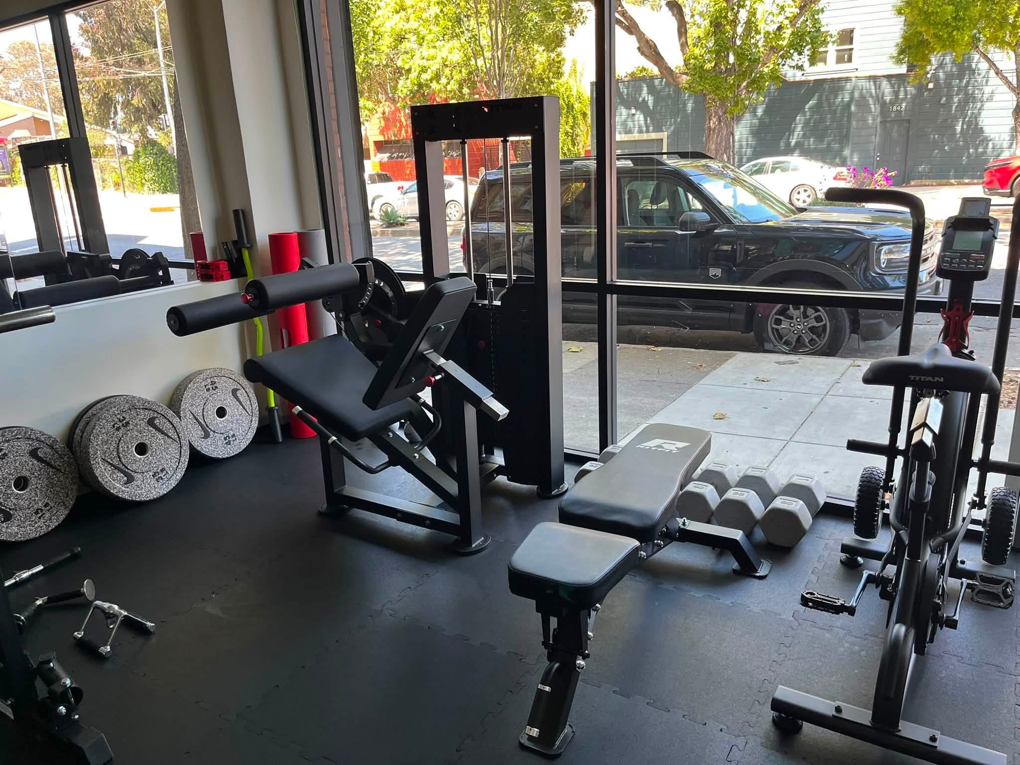 Strength equipment and an adjustable bench beside the studio’s front windows.
